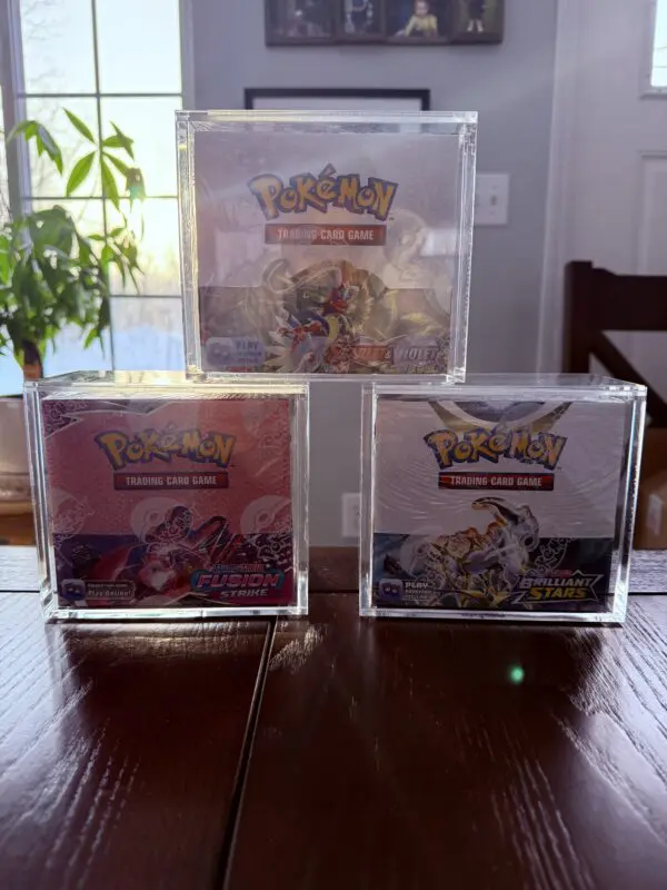 Three Pokémon game cases stacked on a table with a plant in the background.